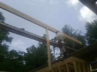 Carpenter setting a ridge beam over a new addition frame — Ice Dam Removal by Roofing Brothers in Walker