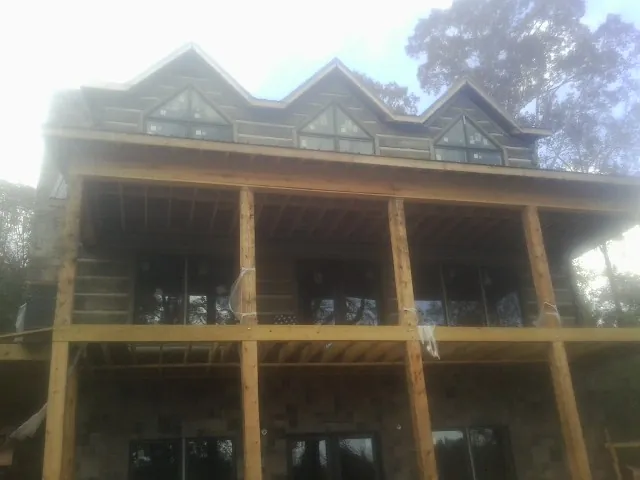 Dormers and porch framing on a large log home under construction — Roof Coating work by our crew in Walker