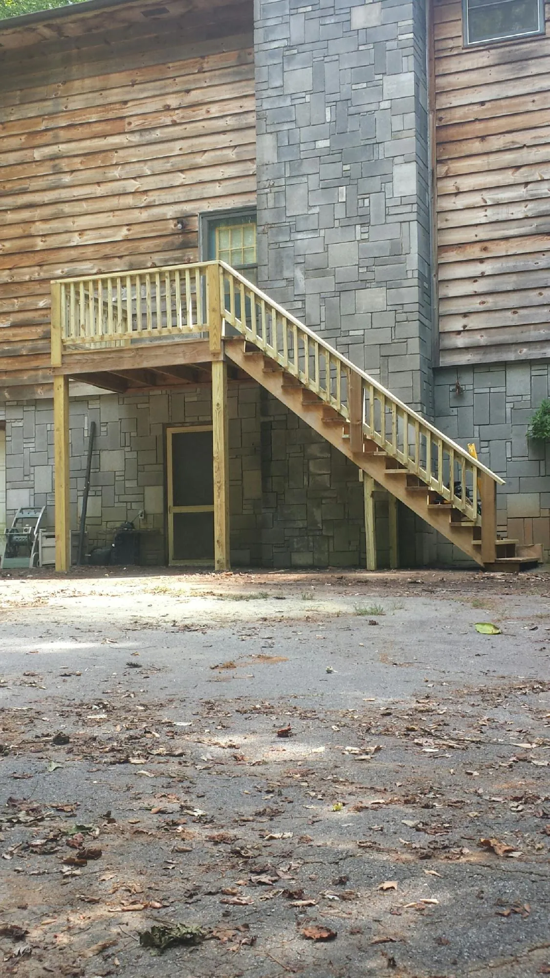 New pressure treated deck and stair landing on a log home in Walker