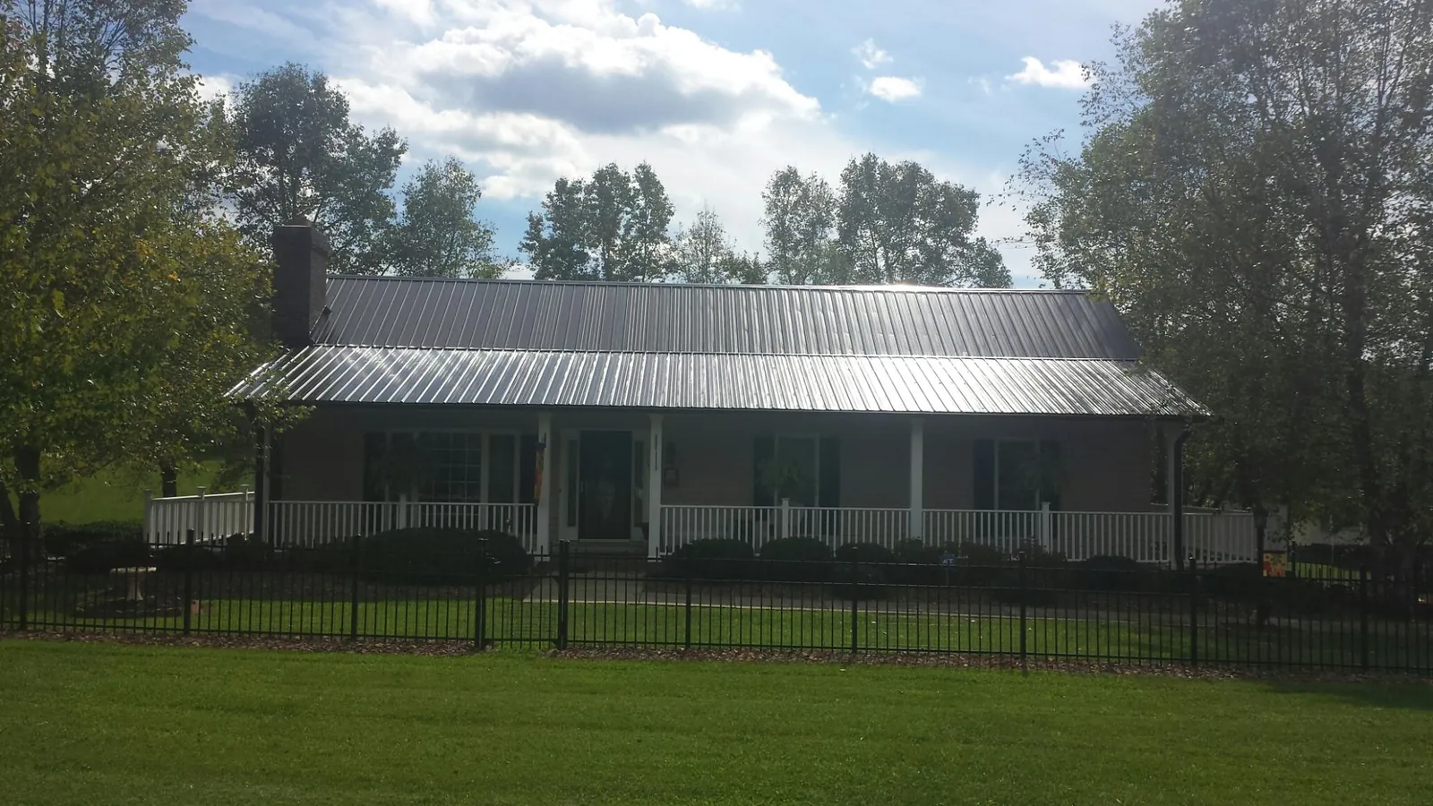 Gray metal roof on a brick ranch with a full width front porch — Gutter Guard Installation work by our crew in Walker